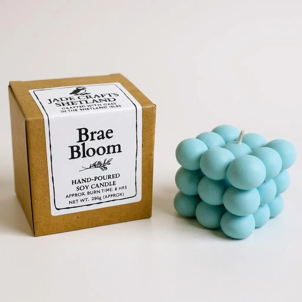 A light blue bubble candle sits next to its brown cardboard box packaging.