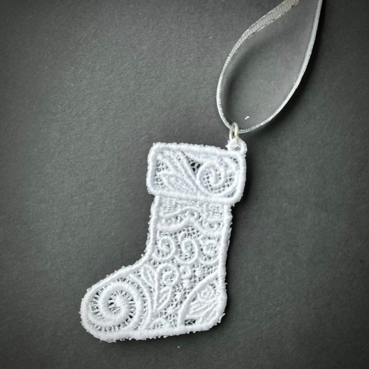 White lace Christmas stocking ornament with a ribbon loop.