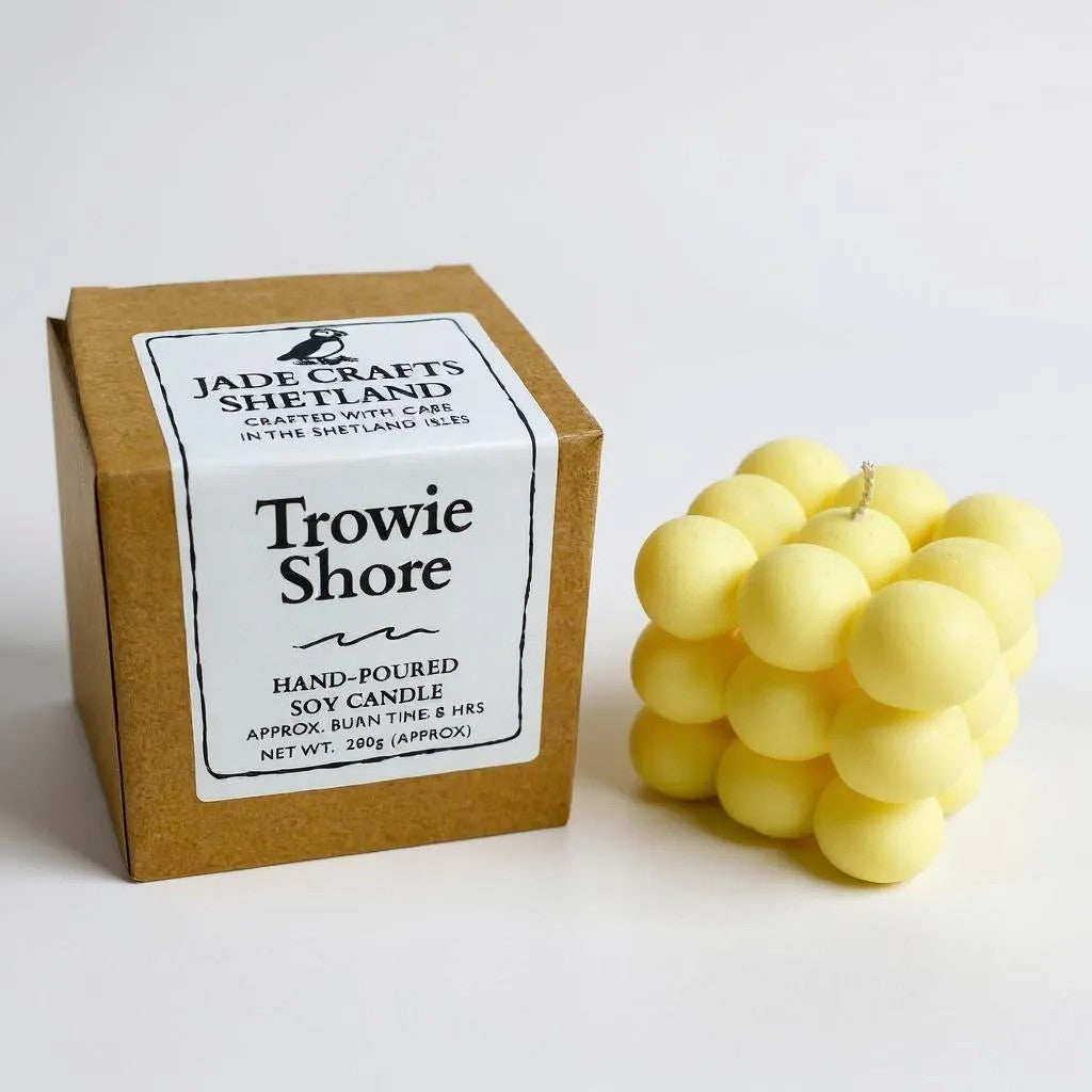 A yellow bubble candle with a box labeled "Trowie Shore" from Jade Crafts Shetland.
