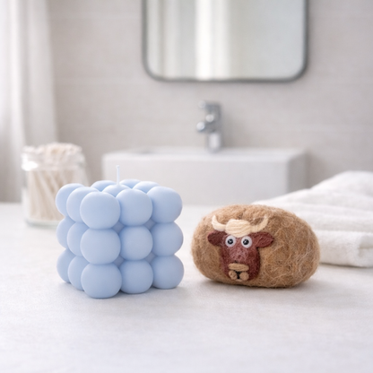 Handmade gift set featuring a light blue bubble candle and a brown felted soap with a cow design.
