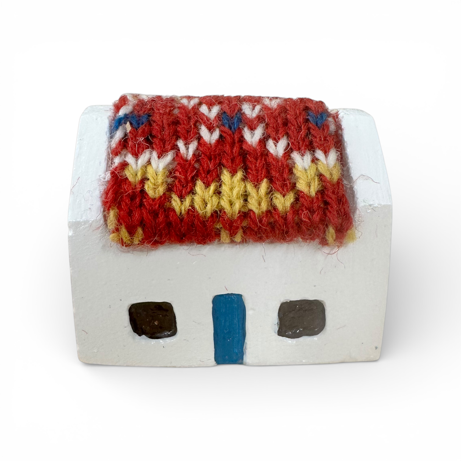 Handmade white wooden croft house with a colorful Fair Isle knitted wool roof.
