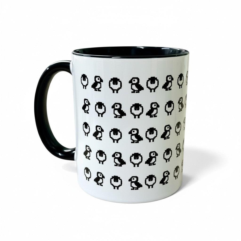 White mug with a repeating pixelated sheep and puffin pattern and a black handle.
