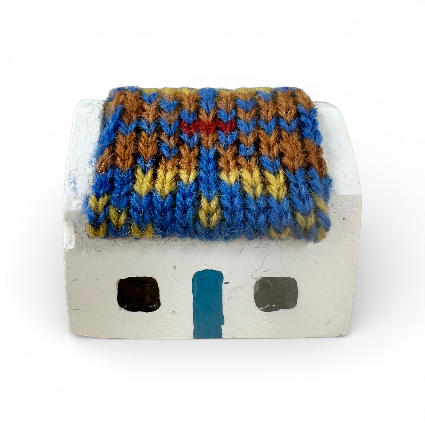 Handmade white croft house with a colorful knitted wool roof in blue, brown, and yellow.