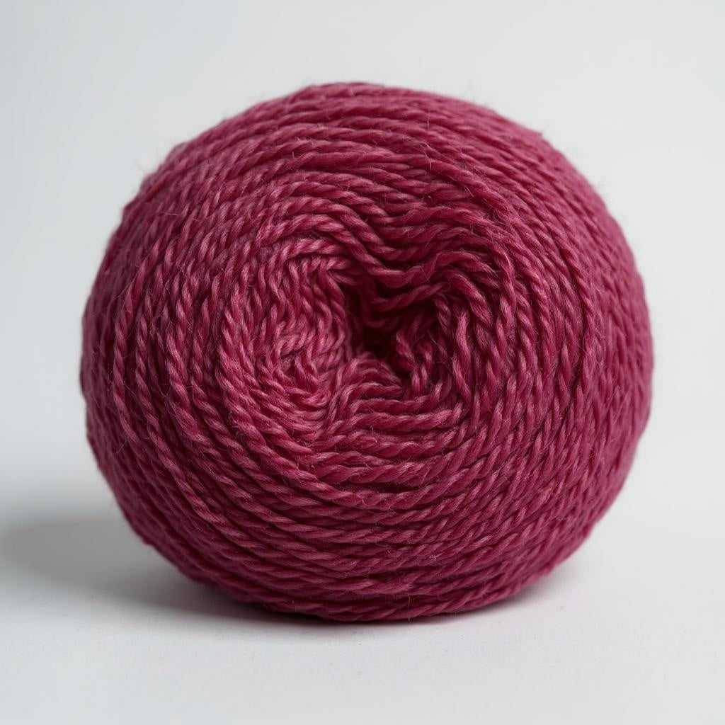 A ball of rich, hand-dyed magenta Shetland wool.