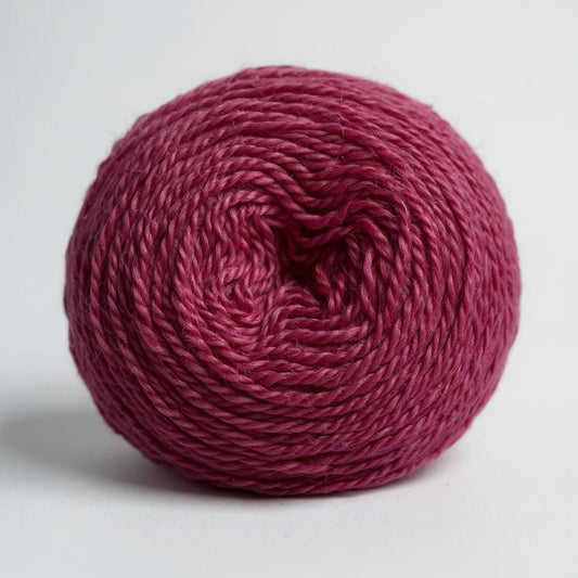A ball of rich, hand-dyed magenta Shetland wool.
