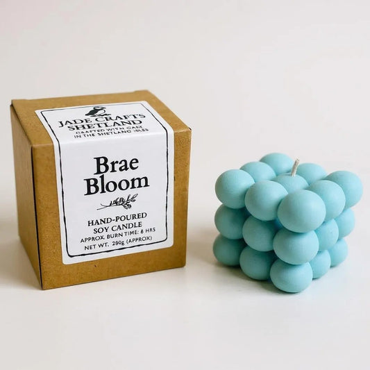 A light blue bubble candle sits next to its brown cardboard box packaging.