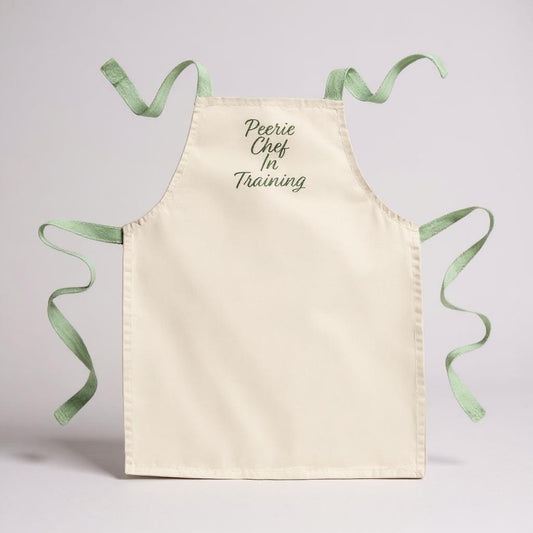 Children's cream apron with green ties and "Peerie Chef In Training" text.