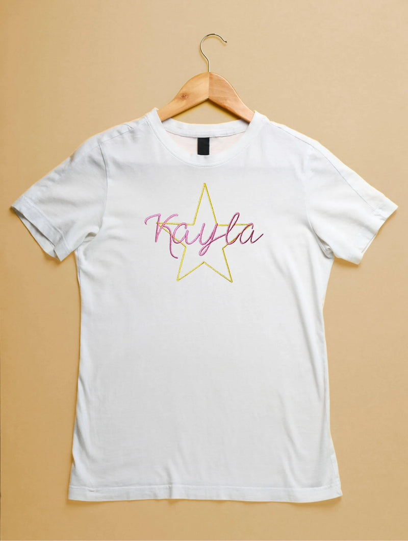 White t-shirt with a yellow star and 'Kayla' text on a beige background