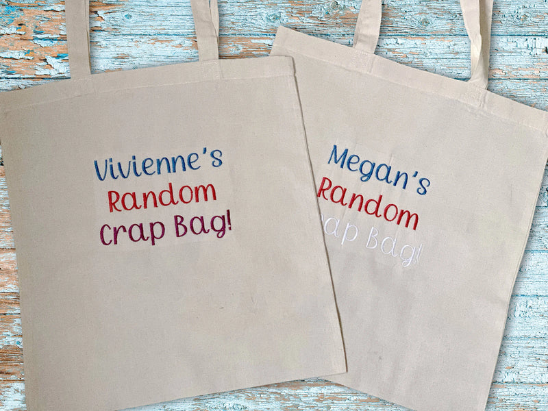 Two beige tote bags with personalized text on a wooden surface