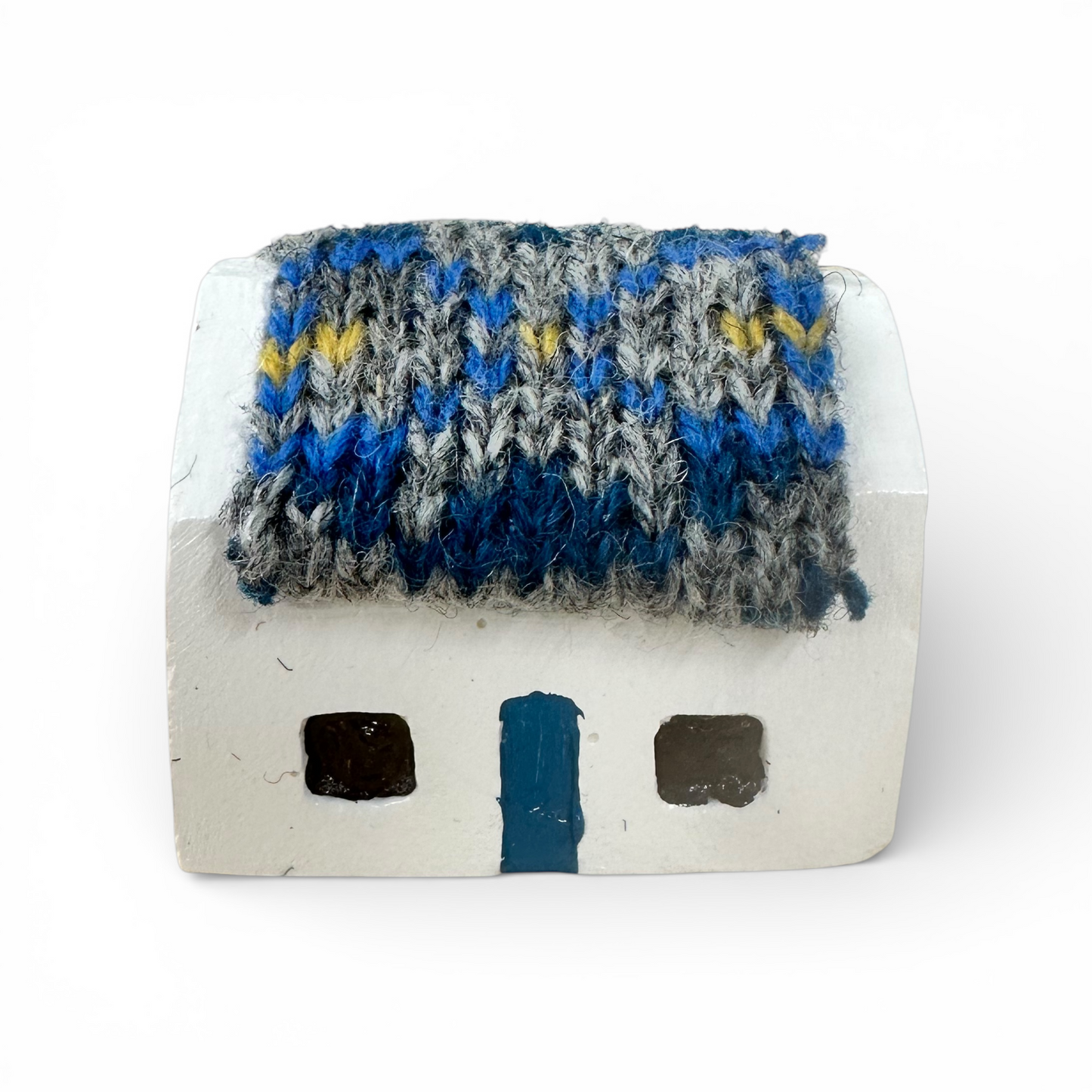 Handmade white croft house with a blue and grey knitted wool roof and a blue door.