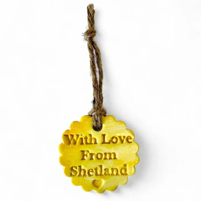 Yellow scalloped clay tag with "With Love From Shetland" and a heart.