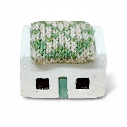 Handmade white croft house with a green and white knitted roof.