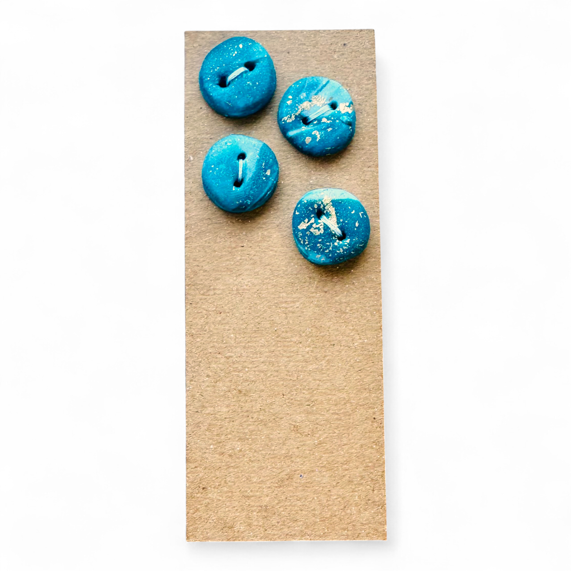 Four handmade turquoise and white clay buttons with gold leaf accents.