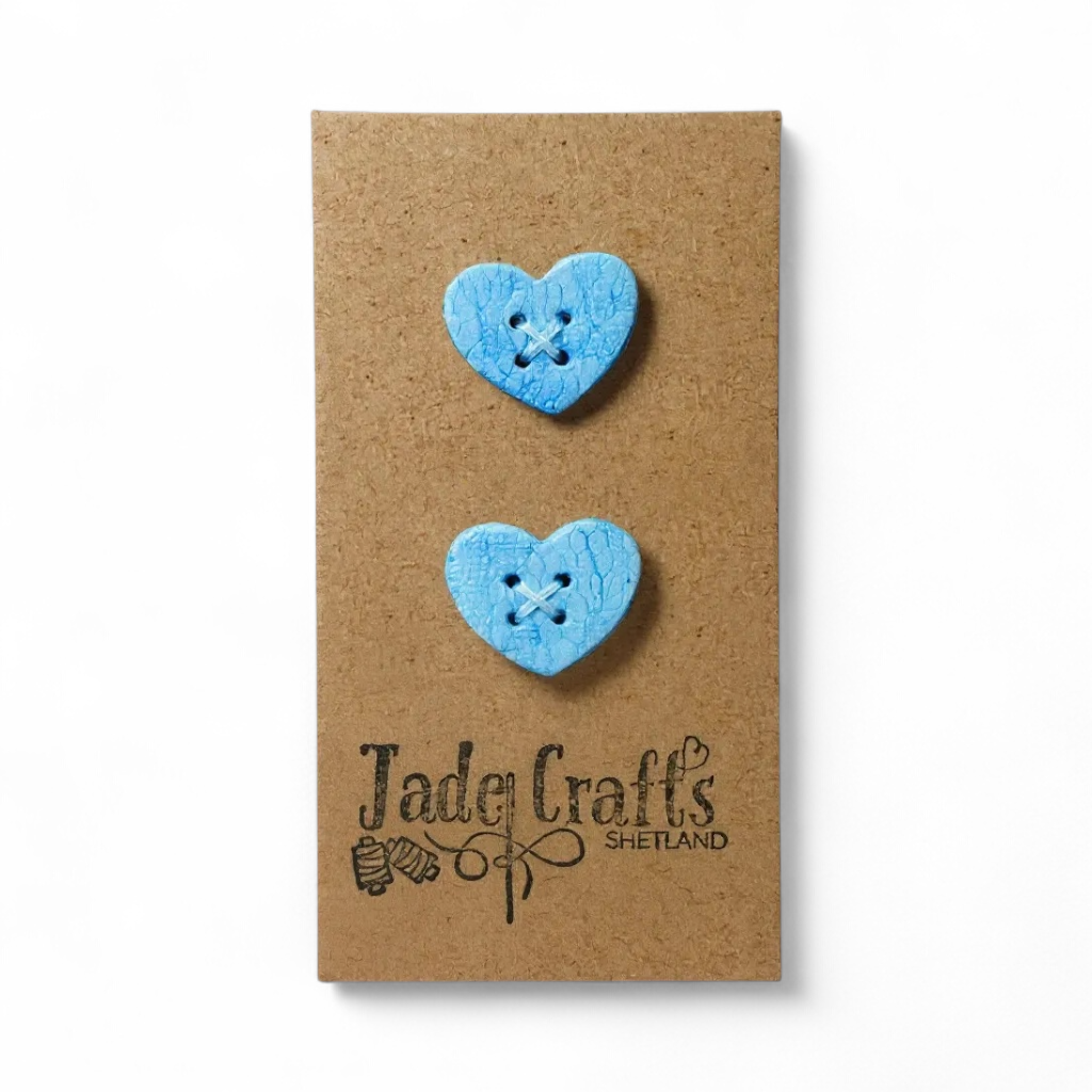 Two handmade blue lace effect heart buttons on a brown card.