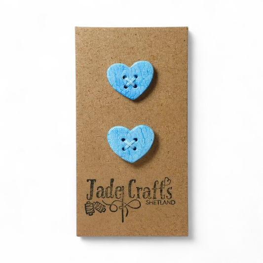 Two handmade blue lace effect heart buttons on a brown card.