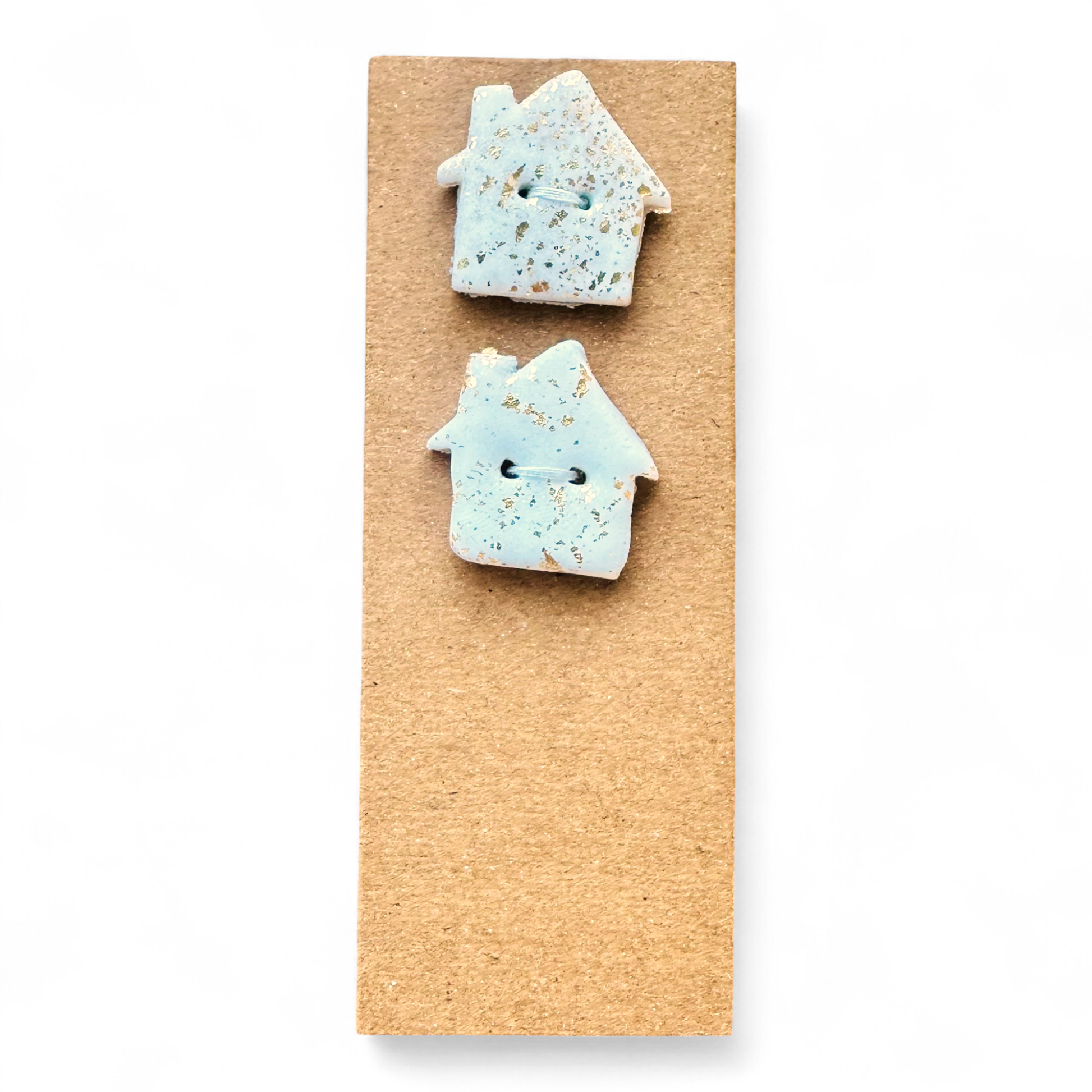 Handmade light blue house-shaped buttons with gold flecks on a brown background.