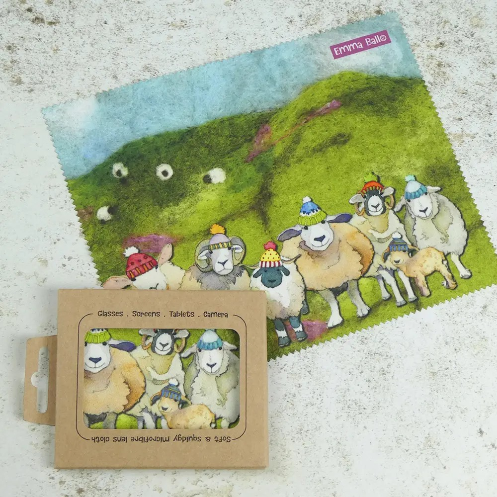 Happy Sheep lens cloth with sheep wearing colorful hats on a grassy hill.
