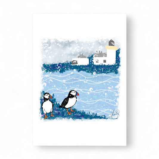 Printed Christmas card featuring two puffins on a snowy cliff with a lighthouse.
