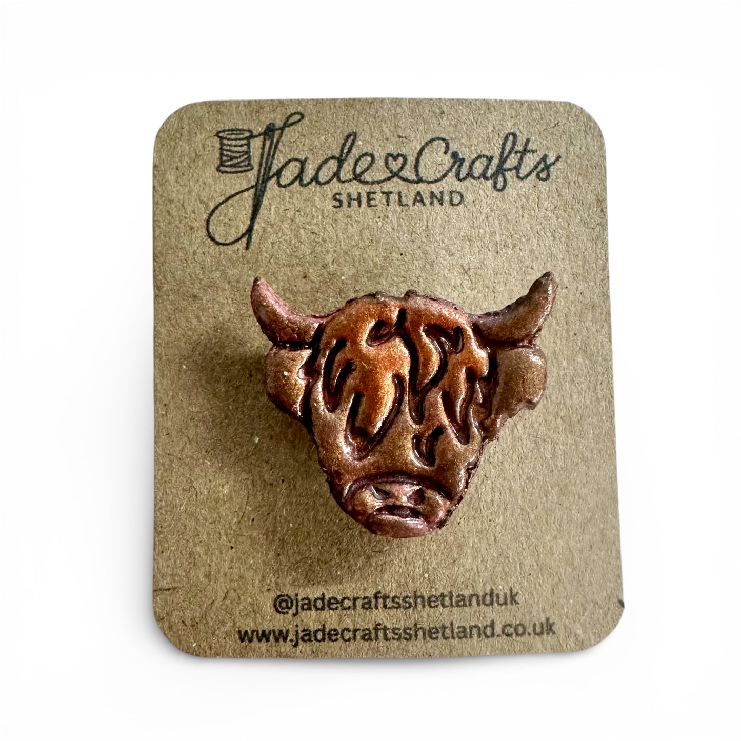Hand-painted clay Highland Cow brooch with a metallic bronze finish on a brown card backing.