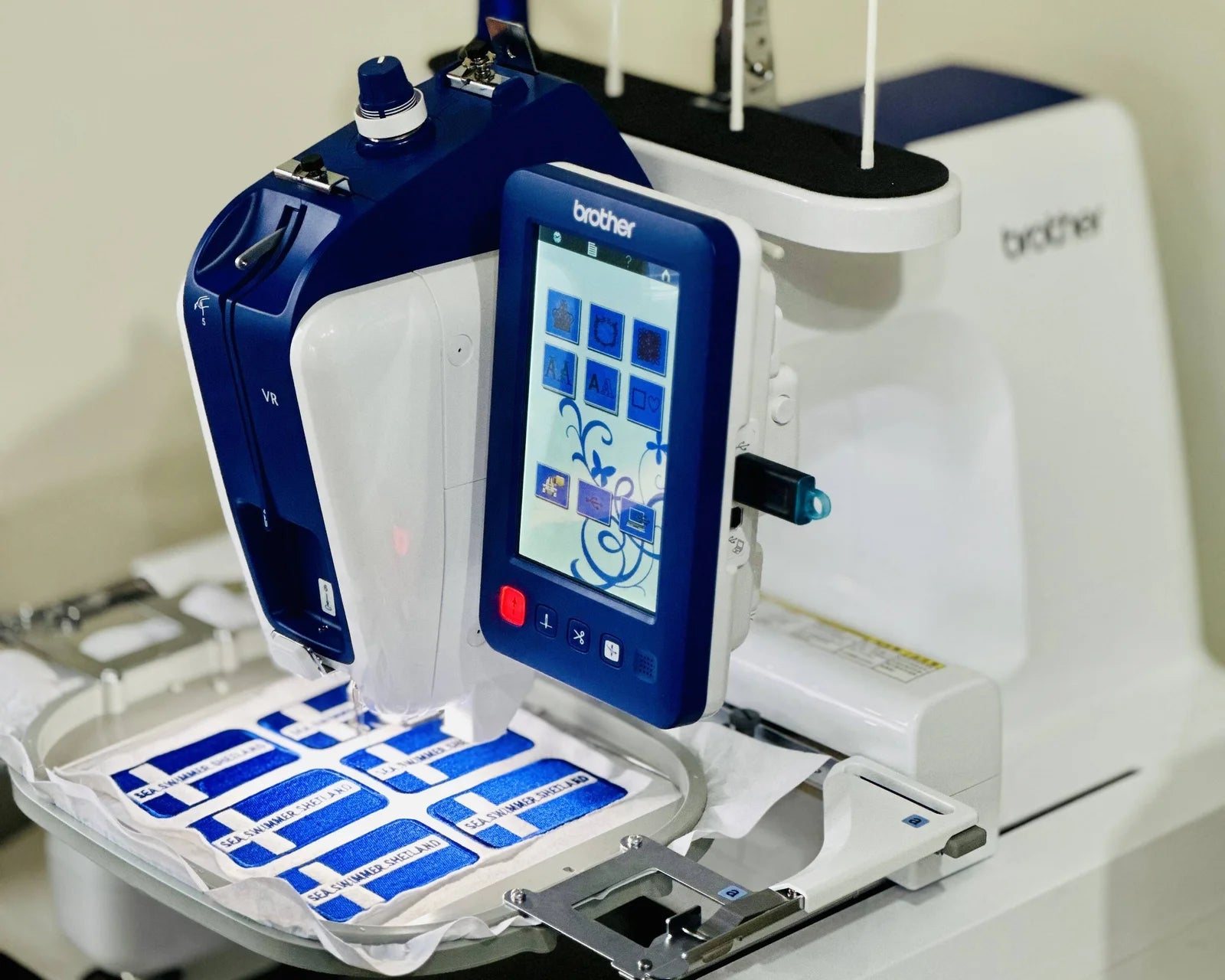 Brother embroidery machine with digital display and blue labels on a white background