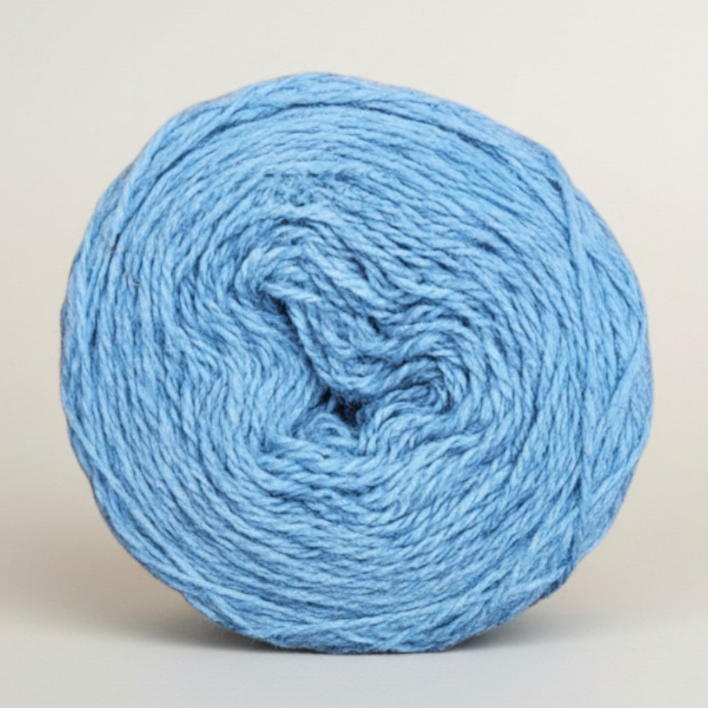 A round cake of light blue Uradale 100% Shetland wool yarn in the Speedwell colorway.