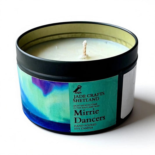 Mirrie Dancers hand-poured soy candle in a black tin with aurora-inspired artwork on the label.