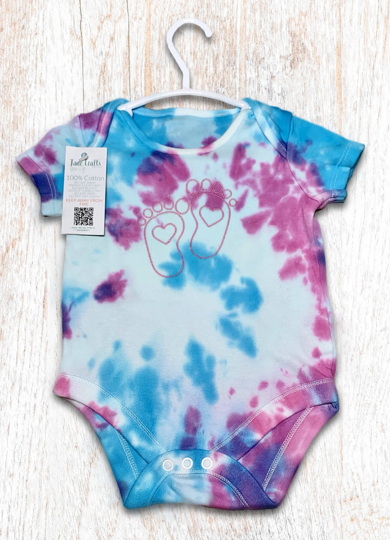 Tie-dye baby onesie with pink and blue patterns on a white background