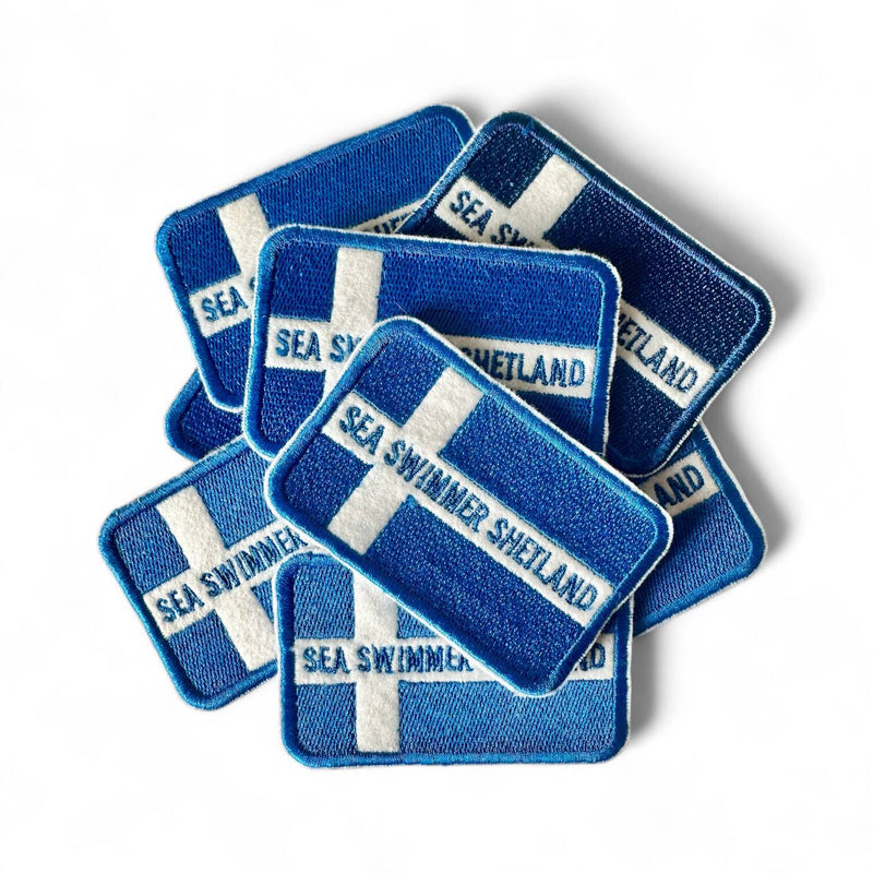 Set of blue and white patches with 'Sea Swimmer Shetland' text on a white background