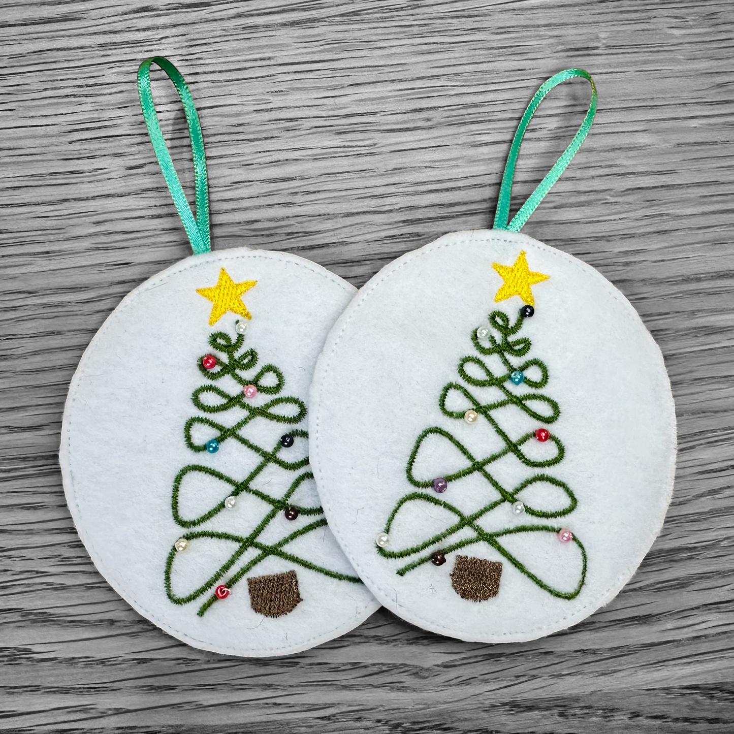 Embroidered Christmas tree decorations with beadwork and yellow stars.