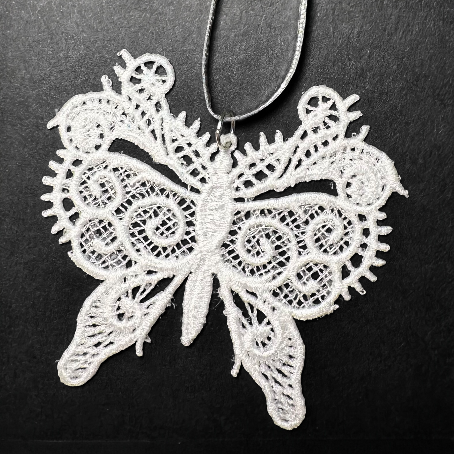 White lace butterfly ornament on a black background.