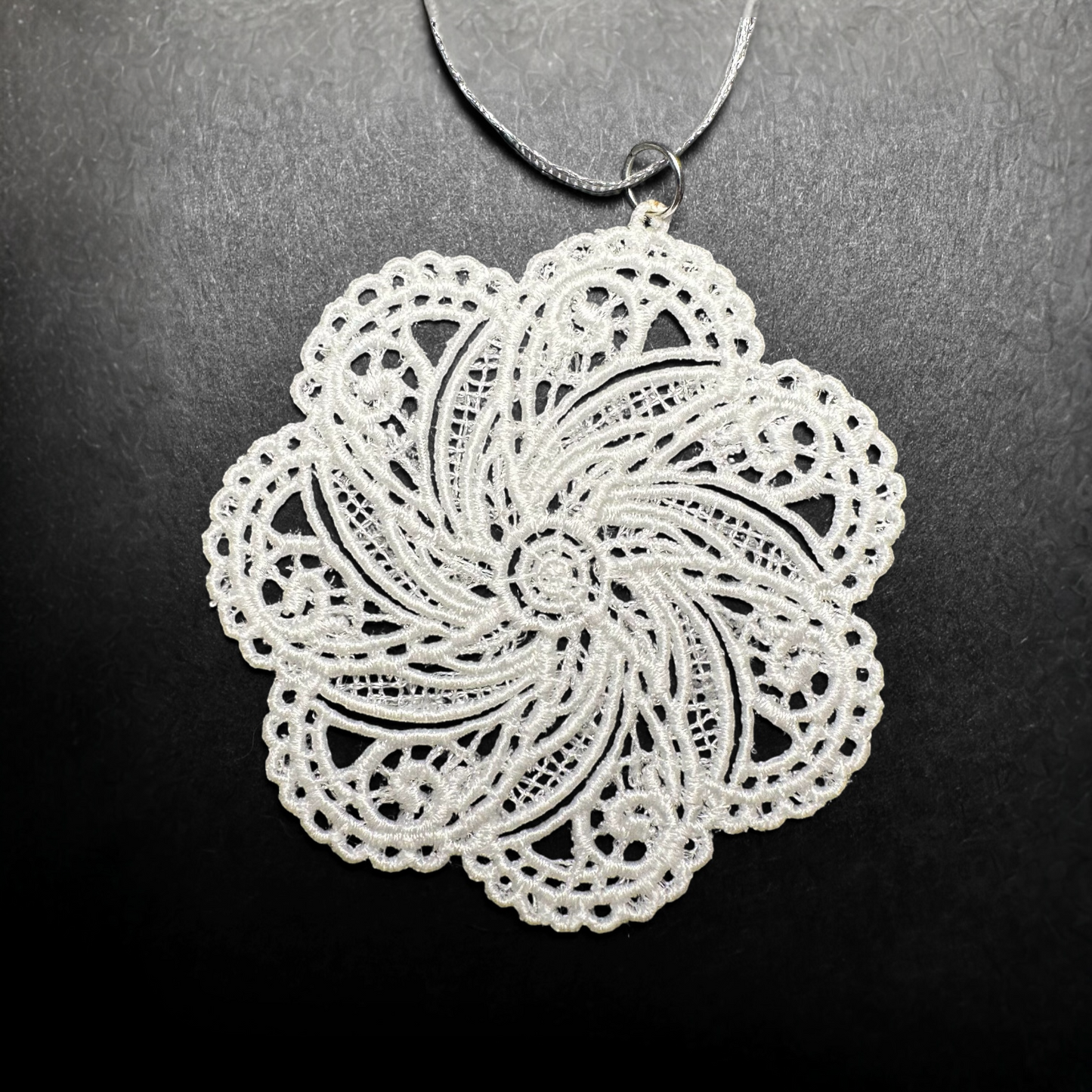 White lace snowflake ornament on a dark background.