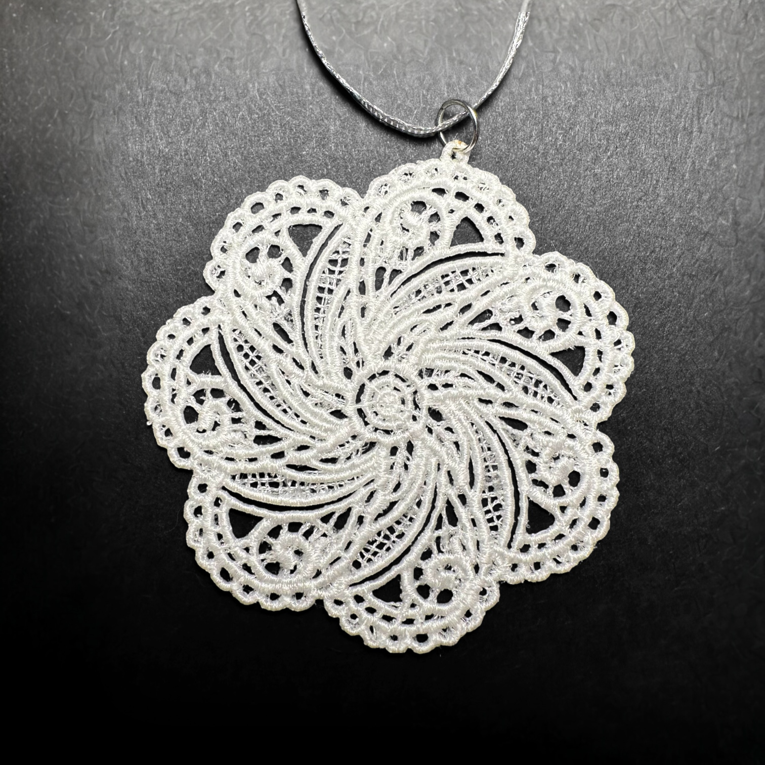 White lace snowflake ornament on a dark background.