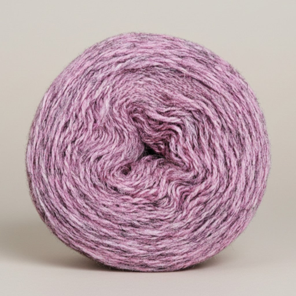 A round cake of Uradale 100% Shetland wool yarn in a heathered sea pink meal colorway.