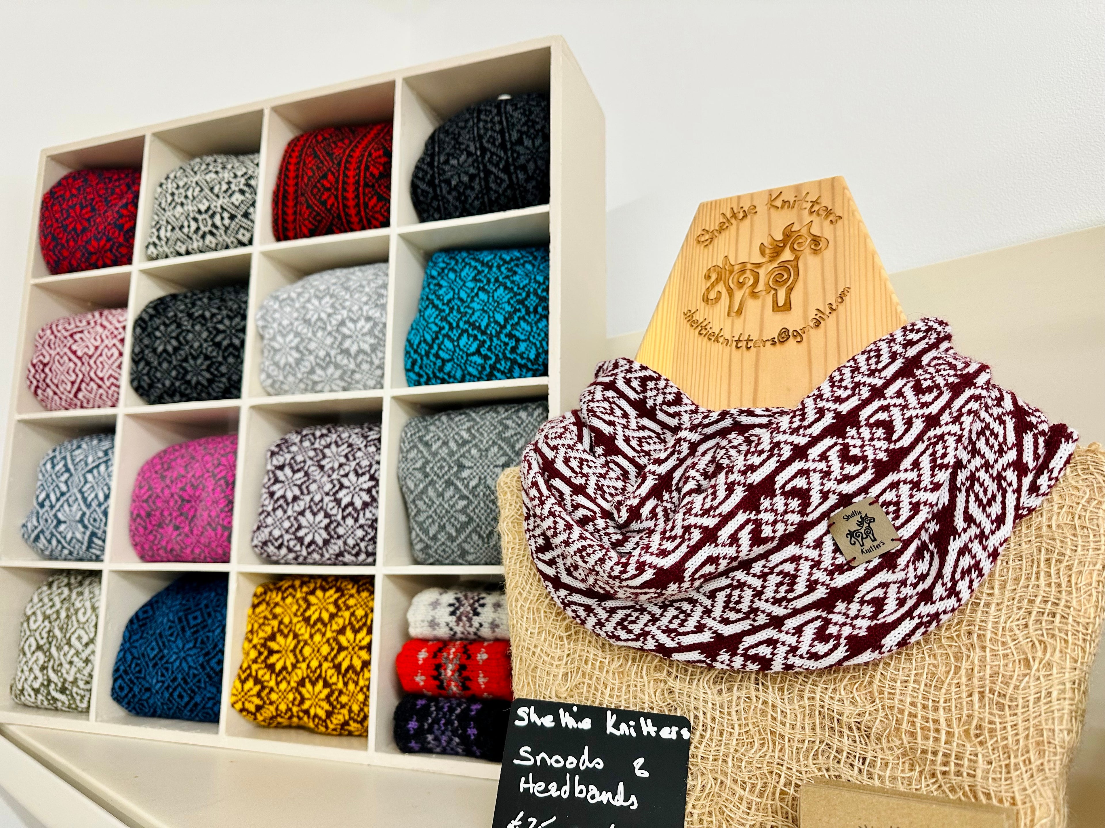Collection of patterned scarves in a wooden display box with a scarf on a mannequin.