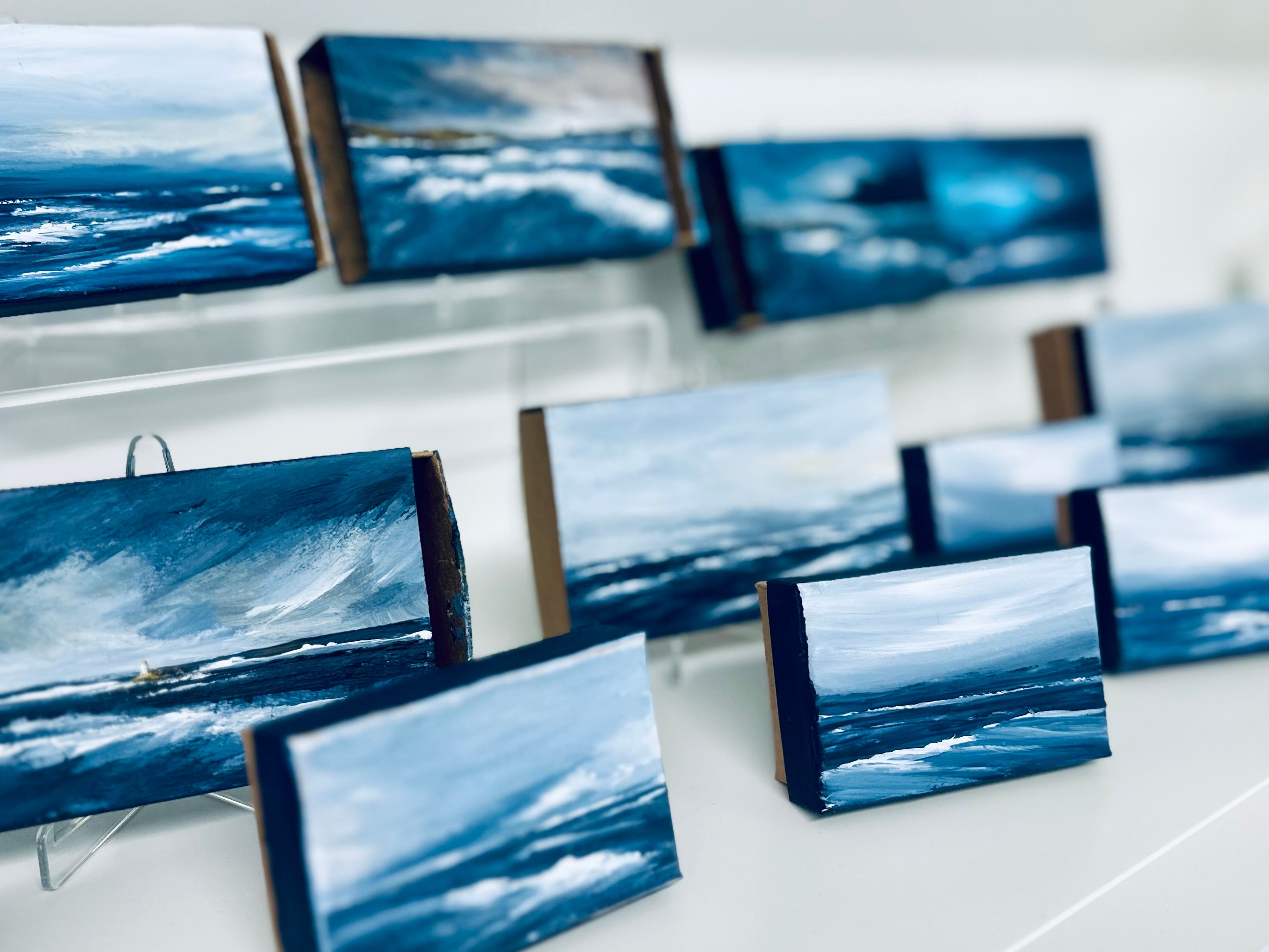 Multiple small canvas prints of ocean scenes displayed on a white surface.