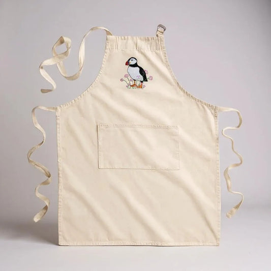 Adult's cream apron with a puffin and flowers embroidered on the chest.