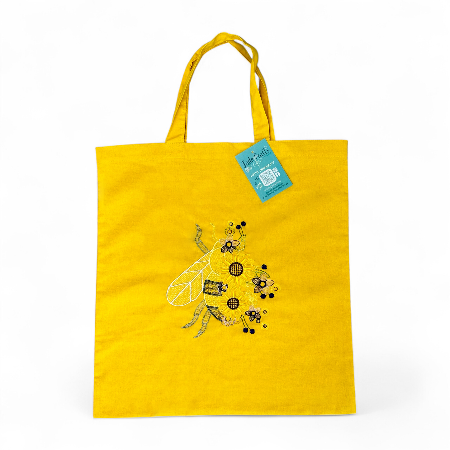 Yellow tote bag with an embroidered bee and flowers.
