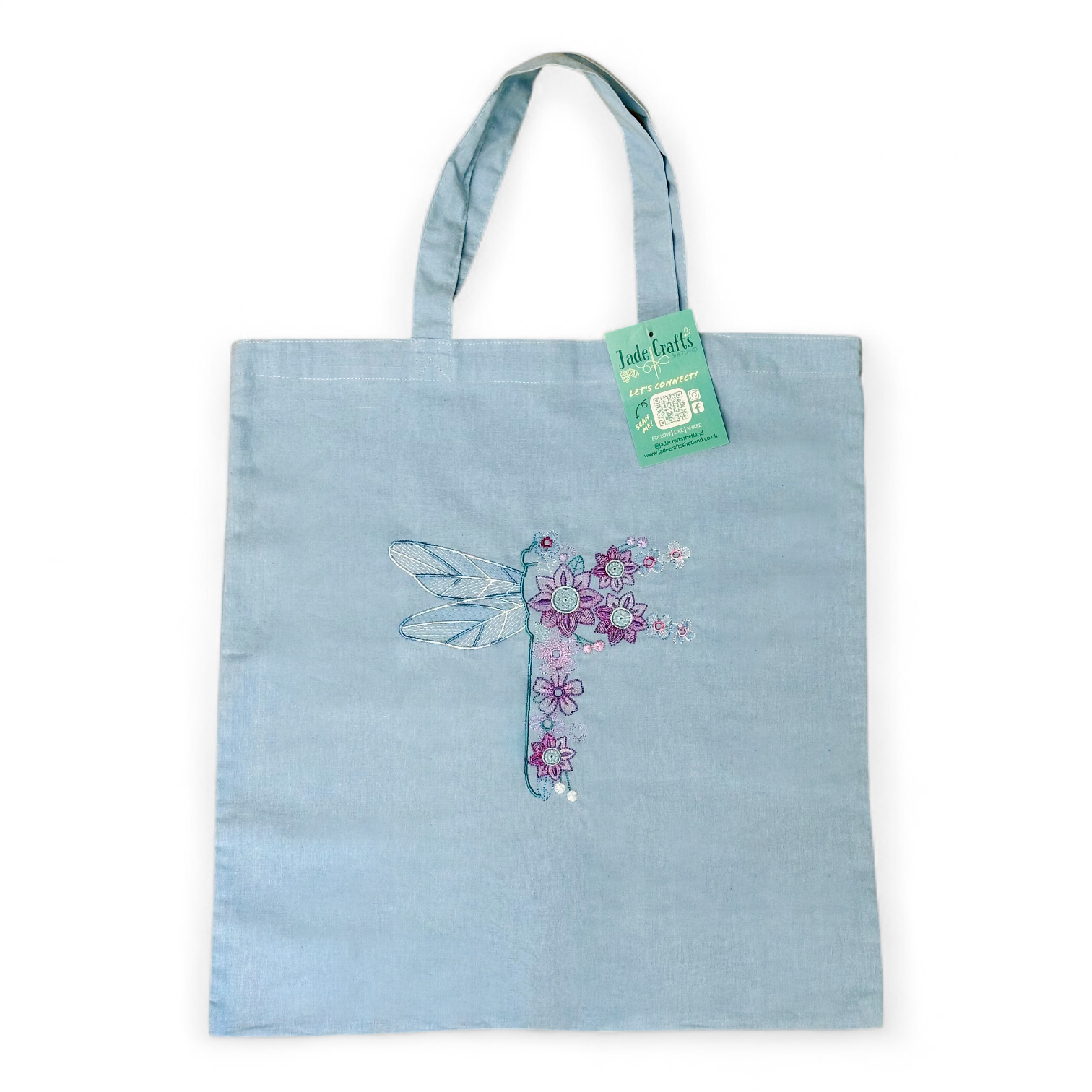 Blue tote bag with embroidered dragonfly and flowers.
