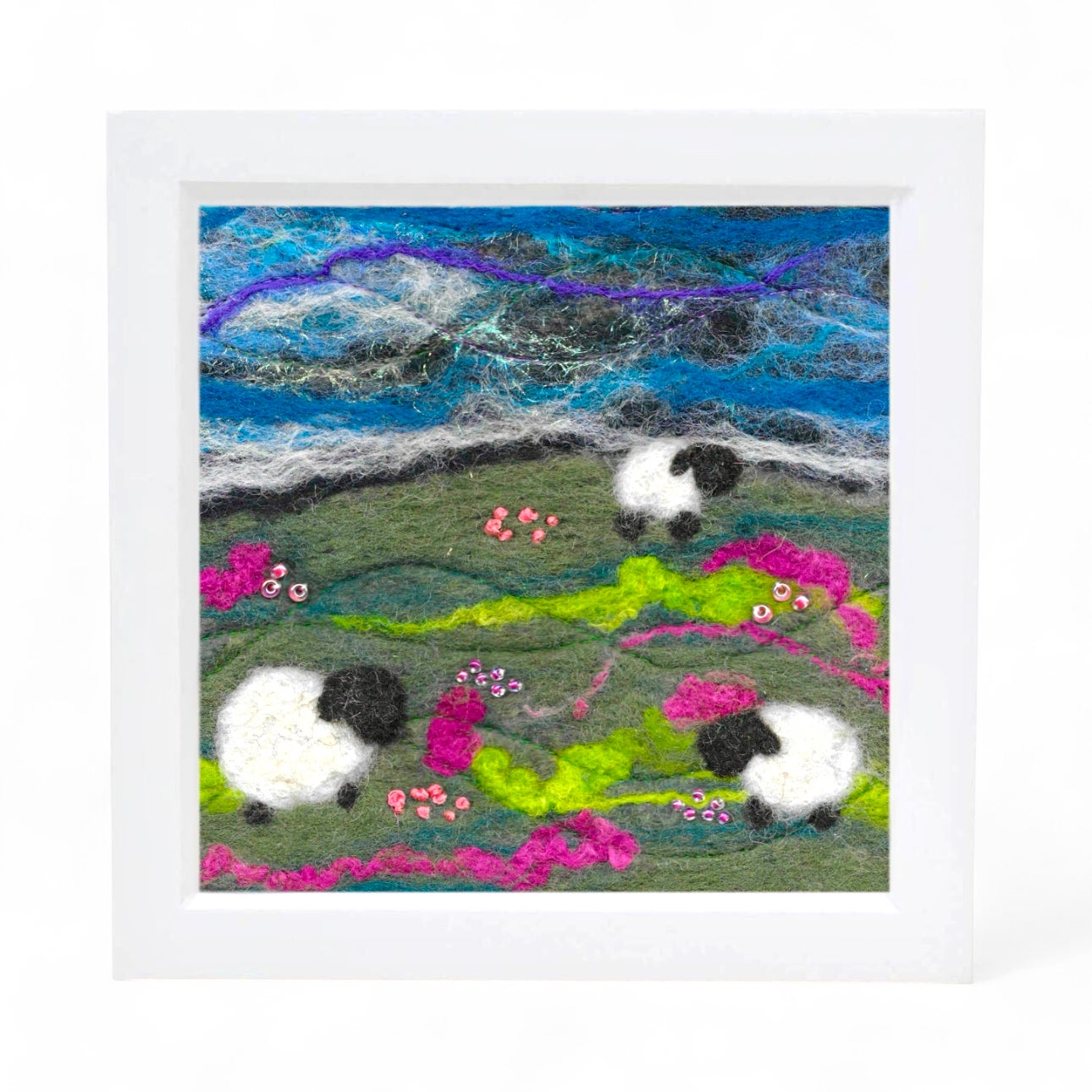 Framed felted picture of sheep in a landscape with a colorful sky.