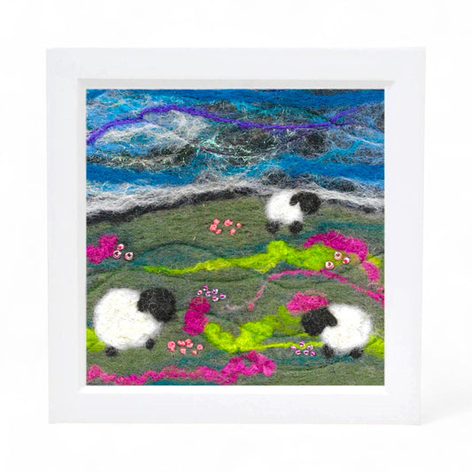 Framed felted picture of sheep in a landscape with a colorful sky.