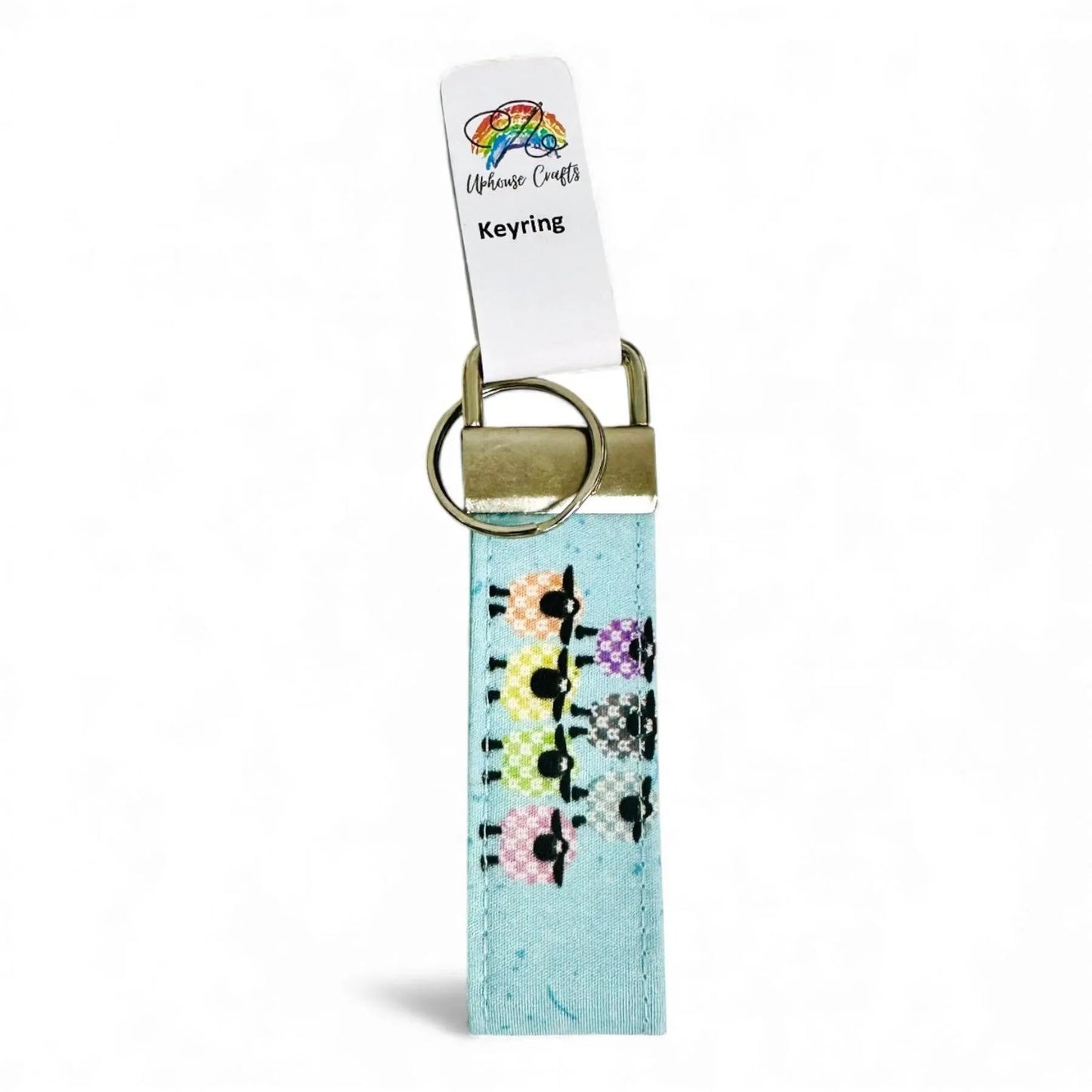 Fabric keyring with a colorful sheep pattern on a light blue background and a metal clasp.