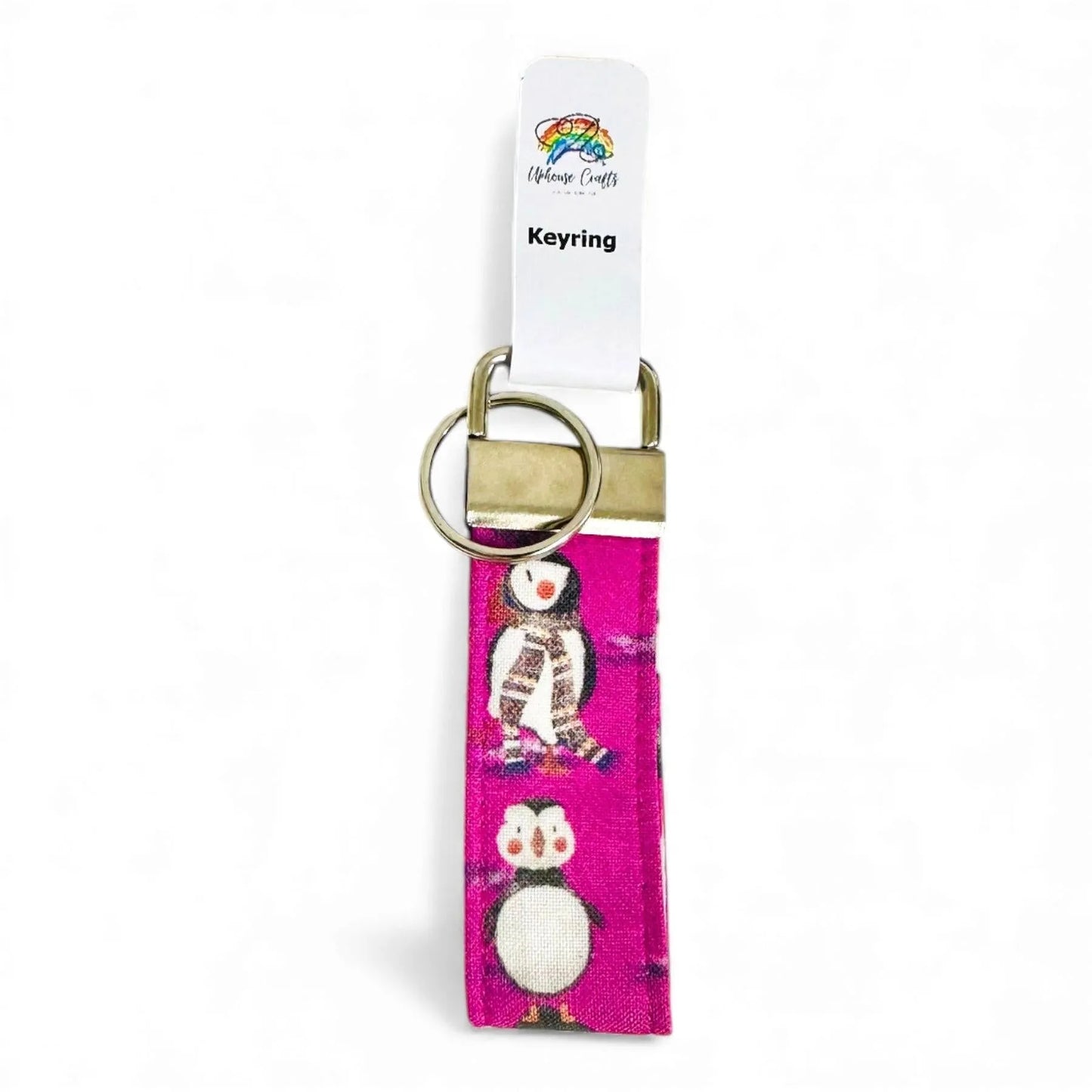 A pink fabric keyring featuring a puffin pattern with a metal clasp and split ring.