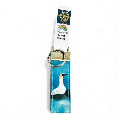 A fabric keyring featuring a gannet bird on a blue background.