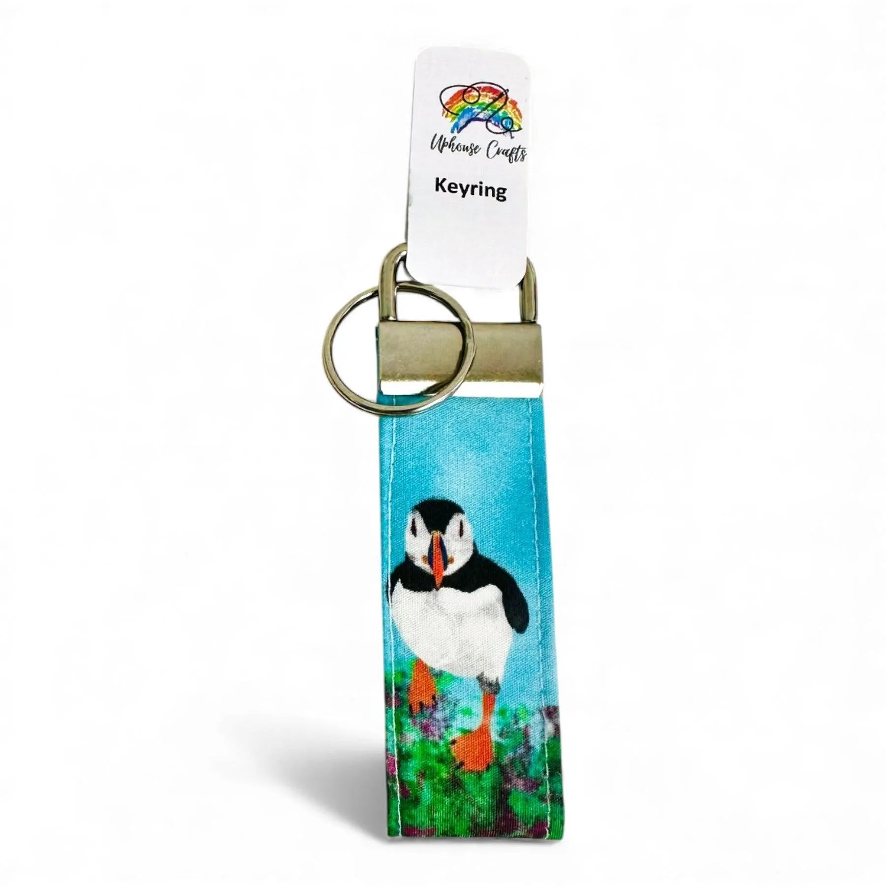 Fabric keyring featuring a colorful puffin illustration on a blue background with a metal clasp.