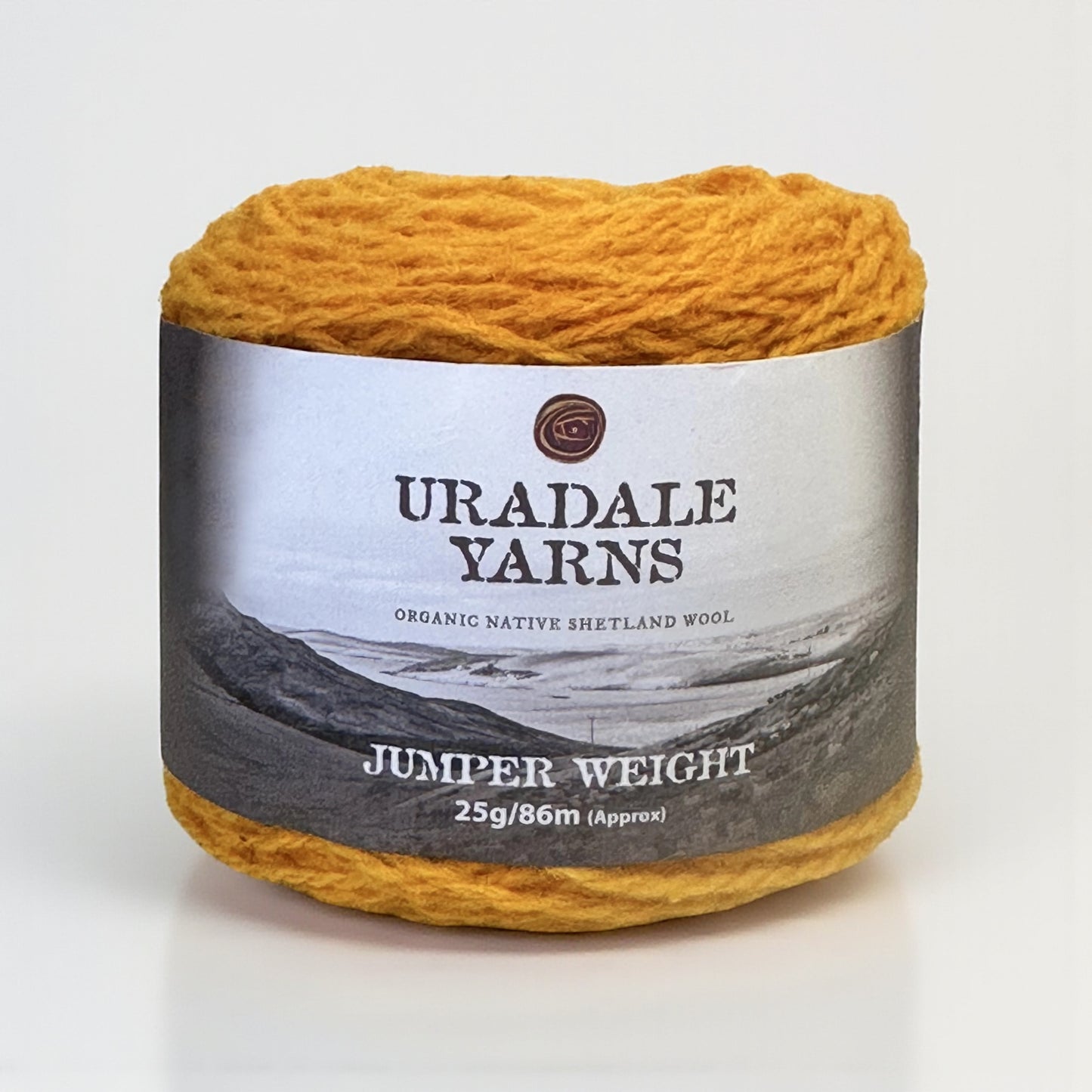 A ball of golden yellow Uradale Shetland wool yarn in the Tormentil colourway with a paper label.