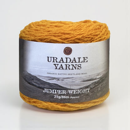 A ball of golden yellow Uradale Shetland wool yarn in the Tormentil colourway with a paper label.
