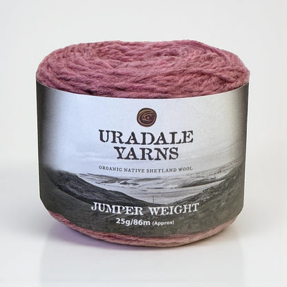 A cake of Uradale Sea Pink Meal Shetland wool yarn with a grey landscape label.
