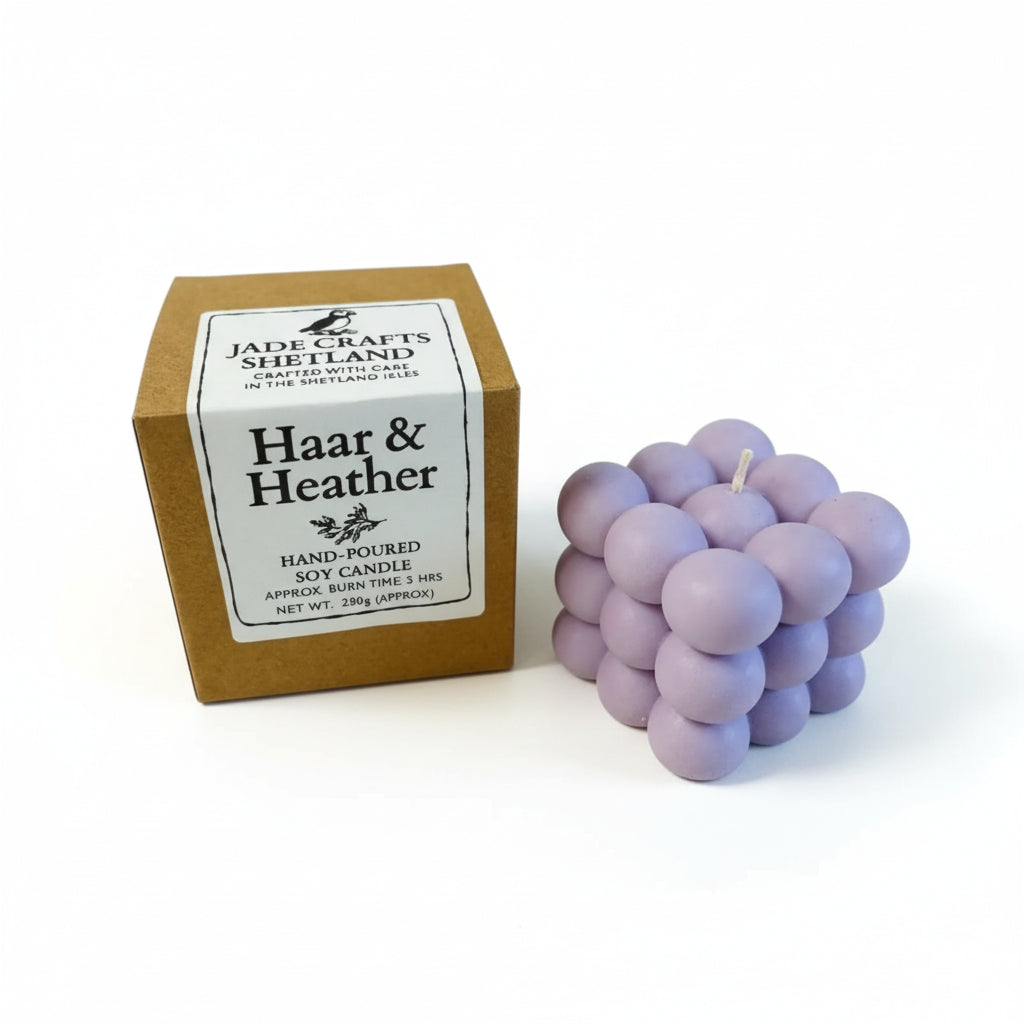 Haar & Heather handmade soy bubble candle in light purple next to its brown cardboard box.