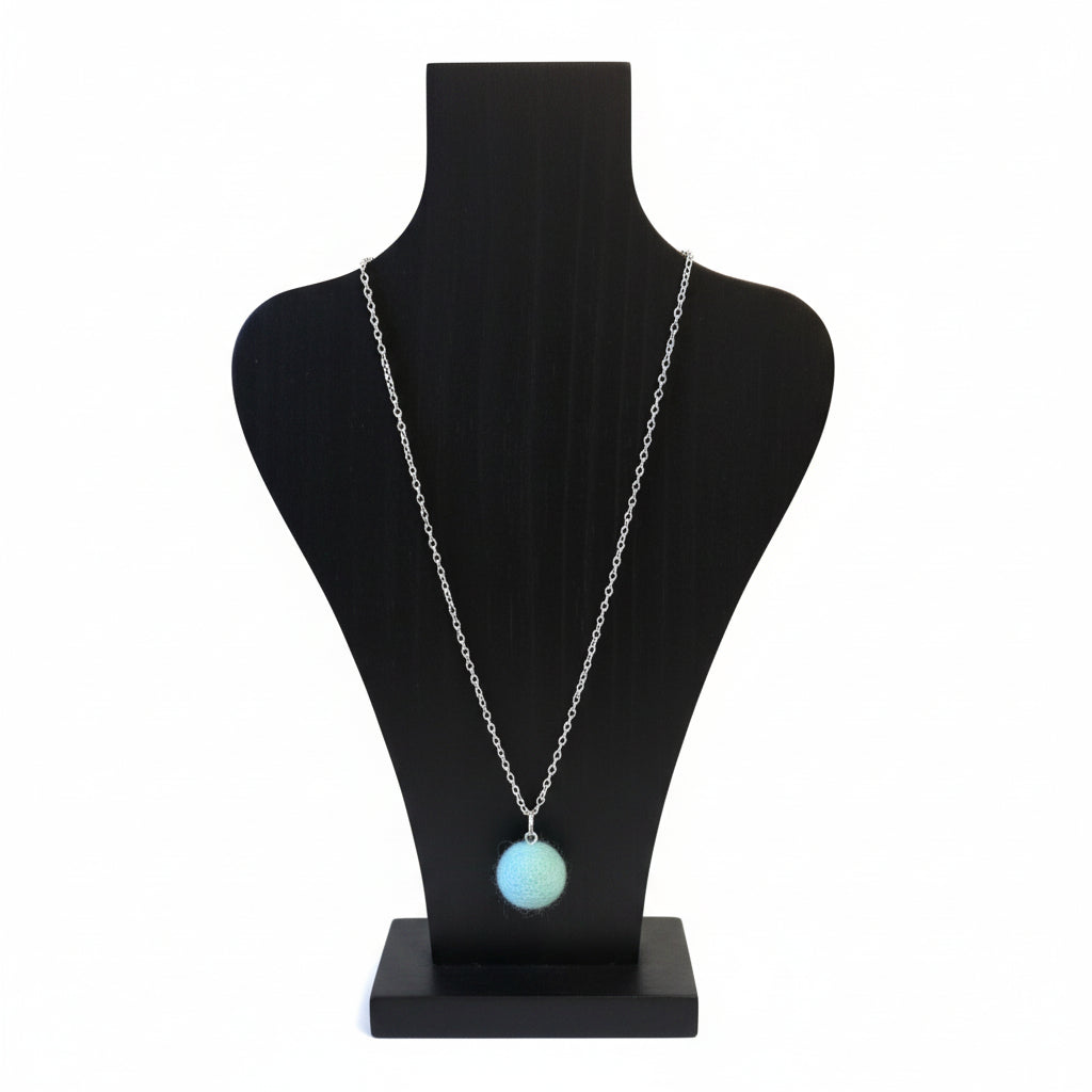 Hand felted light blue wool ball pendant on a silver plated chain displayed on a black bust.