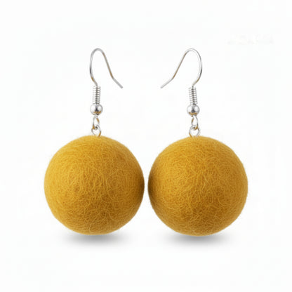 A pair of mustard yellow hand-felted wool ball earrings hanging from silver-colored hooks.